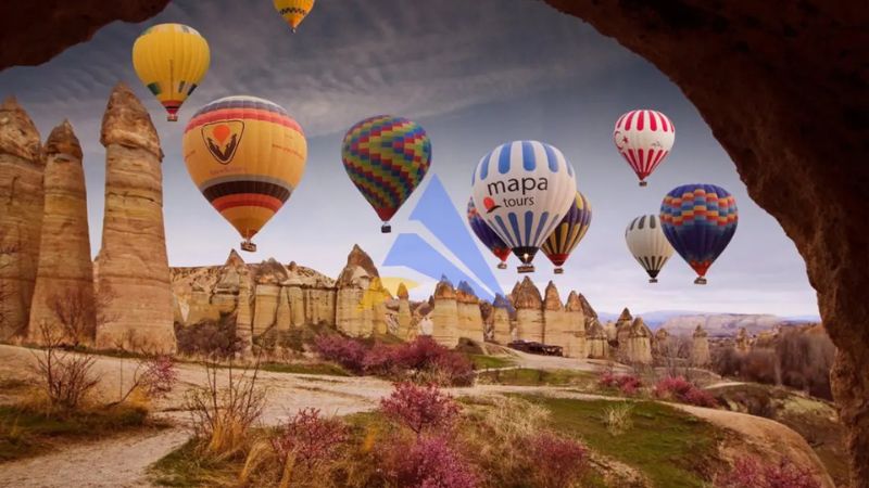 Hot air balloons flying over Cappadocia landscape at sunrise, Turkey